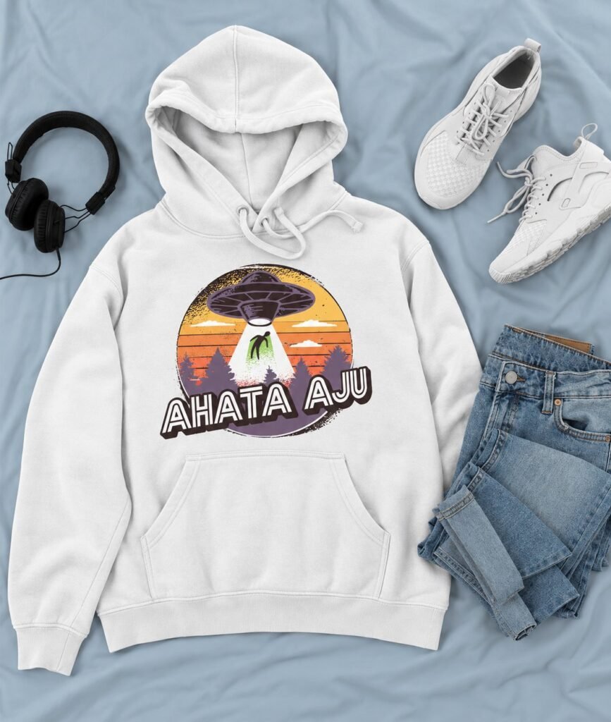 Sudadera con capucha blanca con un ovni bajo un cielo de atardecer y el texto Ahata aju